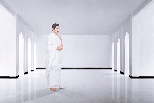 Photo of asian muslim man with ihram cloth praying inside the mosque