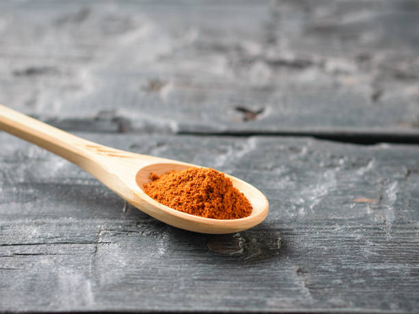 istock Spoon light wood with crushed red pepper on a dark wooden table. 950555988