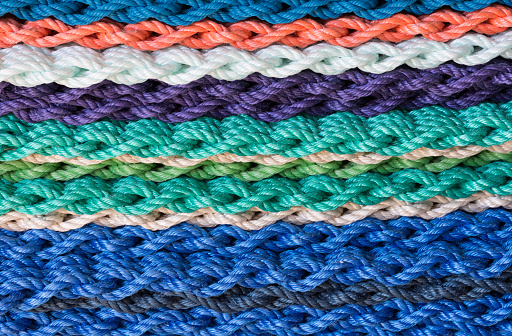 Close up of colorful braided rope made into doormats and stacked on each other. Photographed in natural light.