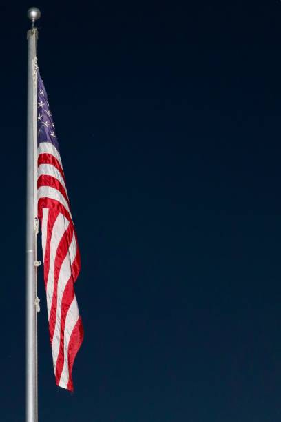 American flag flying at full mast on flagpole nighttime