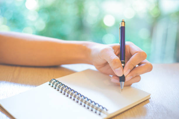 istock Business woman hand is writing on a note pad with a pen in office. 950559664