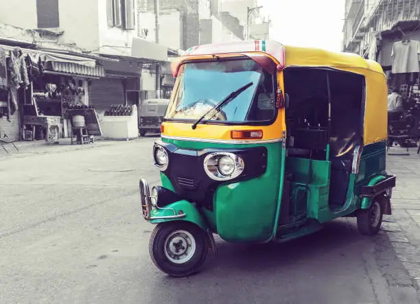 Traditional yellow green tuk tuk taxi on the street. Indian public transport on the streets of new Delhi.