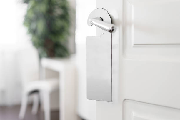 istock Door knob with empty label on a door handle for your text. Empty white flyer mockup hang on door handle. Leaflet design on entrance doorknob. Dont disturb sign. Hotel room clear hanger. blank 950573658