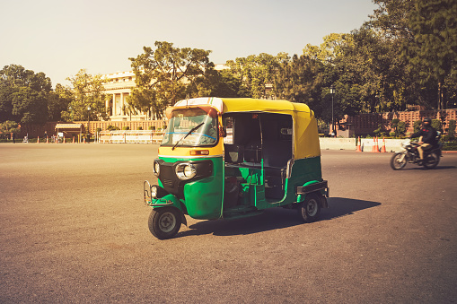 Moto-Rickshaw, New Delhi, India. Indian taxi stands on the street against the backdrop of the presidential Palace. Expensive area of the city.