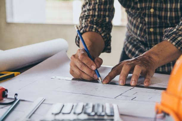 istock Concept architects,engineer holding pen pointing equipment architects On the desk with a blueprint in the office, Vintage, Sunset light.Selective Focus 950577820