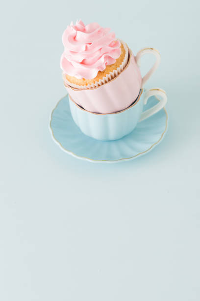 istock Cupcake with gentle pink cream decoration in two cups on blue pastel background. 950582398