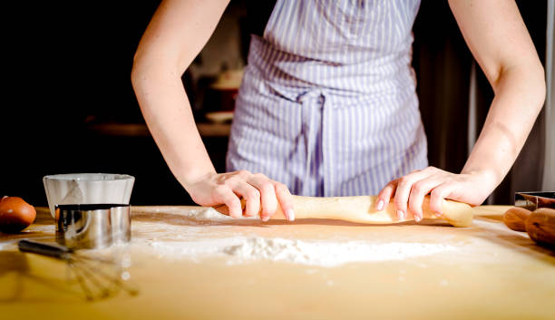 istock Female hands rolling out dough on kitchen table, close up 950582616