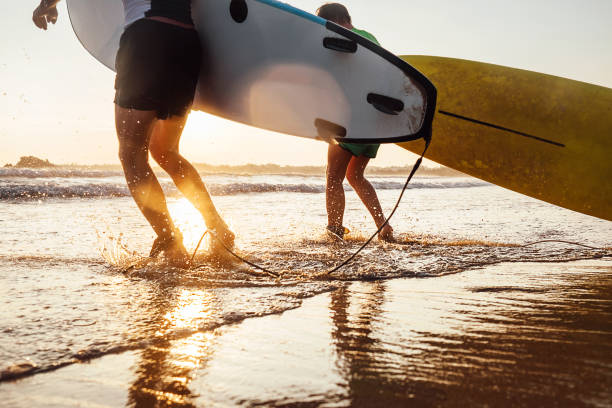 istock Son and father surfers run in ocean waves with surfing boards 950587852