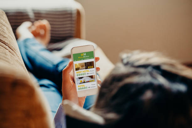 istock Woman using a mobile phone to search hotel for vacation while rest on a sofa at home. 950589292