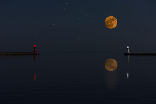Full moon rising over the sea and the lighthouse with copy space.