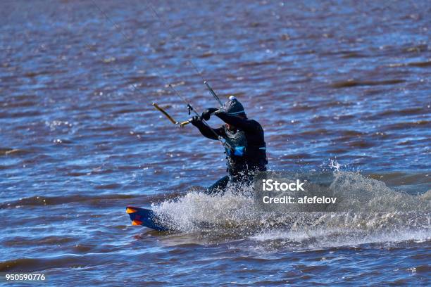 A Male Kiteboarder Rides On A Board Along The River He Performs Various Exercises While Moving On Water Water Still Muddy River The Ice Has Just Melted Sunny Spring Day Stock Photo - Download Image Now