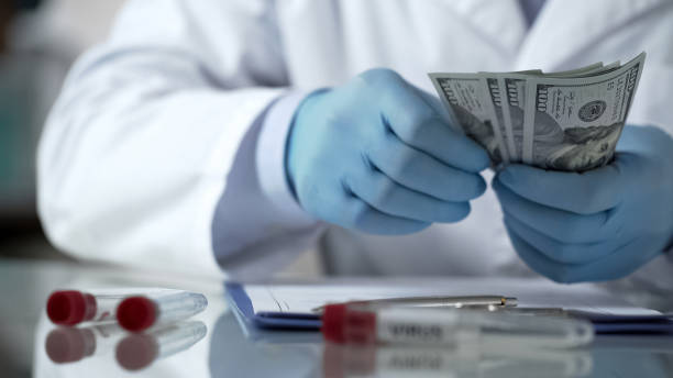 istock Doctor hands counting money on table, financing clinic experiments, bribery 950594450