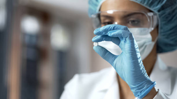 Female chemist looking at white pill, new medication testing in laboratory