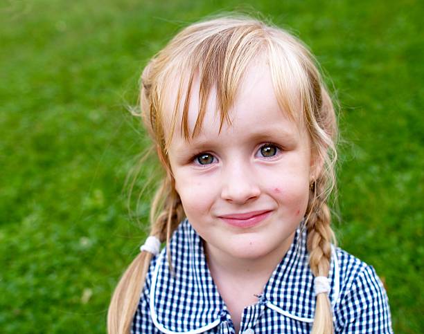 Studio close-up portrait of a 10 year old blonde girl in a pink sundress on a blue background