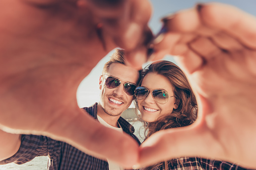 Romantic couple in love gesturing a heart with fingers