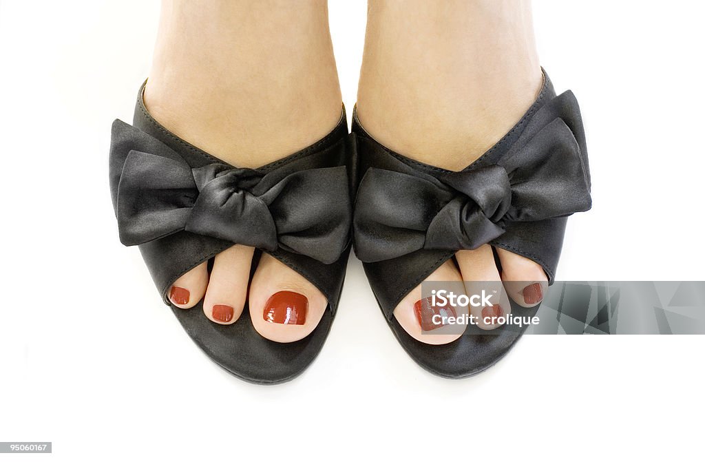 Manicured red toes in black shoes over a white surface Female legs in black sandals. Close up Beauty Stock Photo