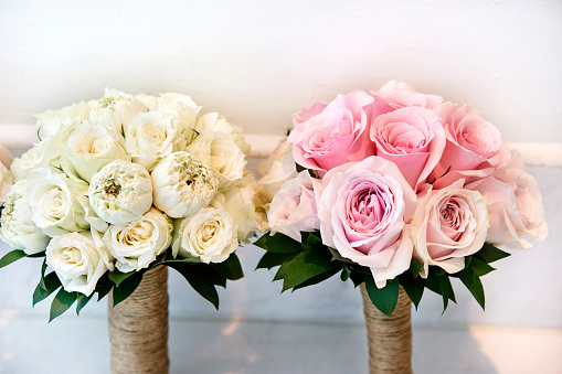 The bouquet from white cream and pink roses on the white wall