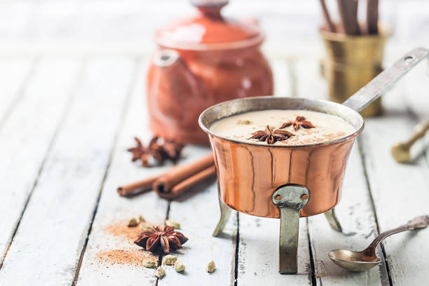 Indian masala chai tea Indian masala chai tea, spiced tea with milk in a copper pot over white wooden background Cardamom stock pictures, royalty-free photos & images