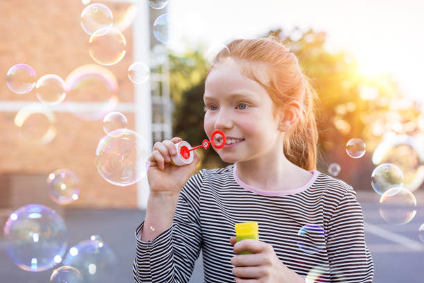 istock Cute girl playing with soap bubbles 950605038