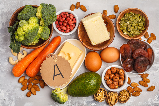 Healthy food nutrition dieting concept. Assortment of high vitamin A sources. Carrots, nuts, broccoli, butter, cheese, avocado, apricots, seeds, eggs.