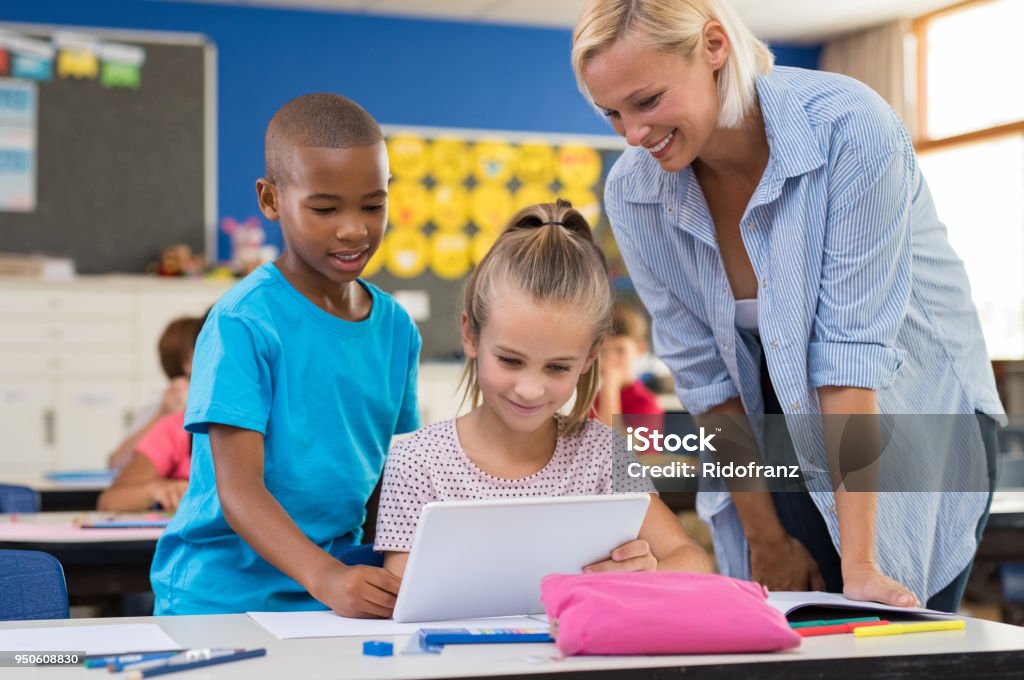 Niños con tableta digital en el aula - Foto de stock de Maestro libre de derechos