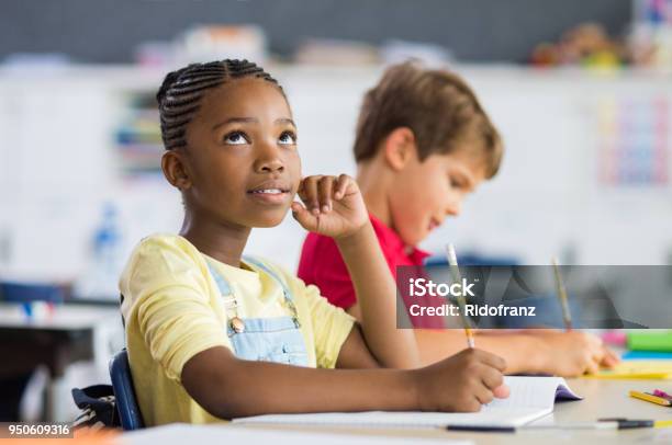 African Girl Thinking In Class Stock Photo - Download Image Now - Child, Contemplation, Writing - Activity