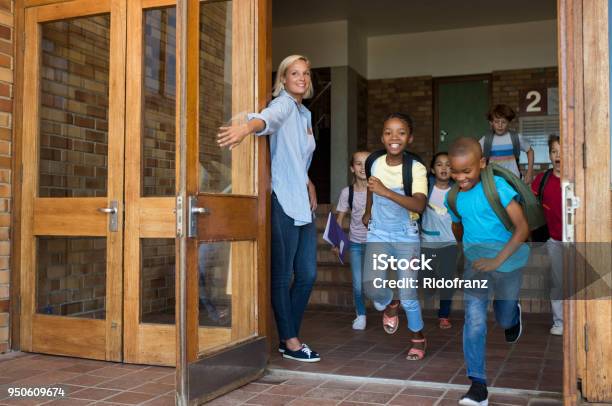 Gruppo Di Bambini Delle Elementari Che Corrono Fuori Dalla Scuola - Fotografie stock e altre immagini di Edificio scolastico