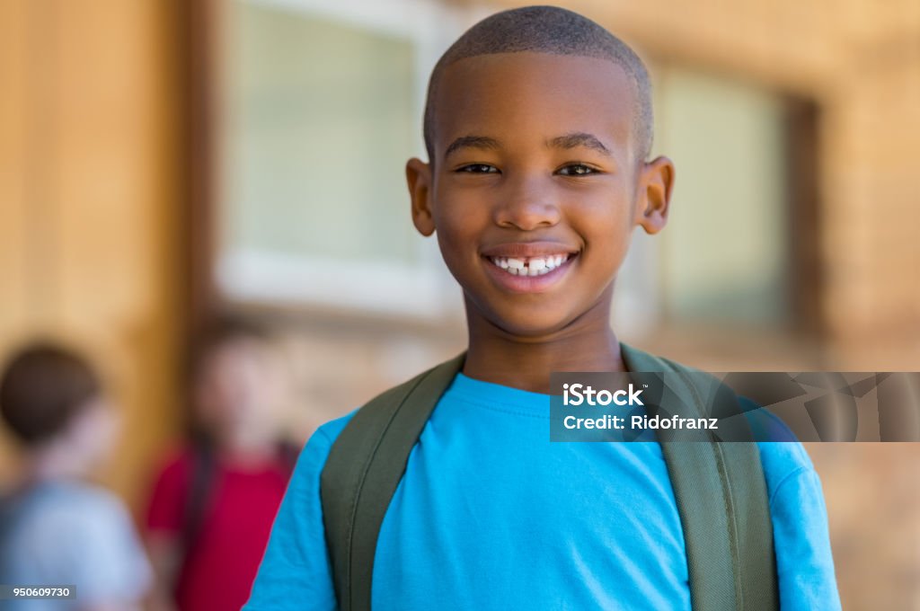 Smiling african school boy Smiling african american school boy with backpack looking at camera. Cheerful black kid wearing green backpack with a big smile. Elementary and primary school education. Child Stock Photo