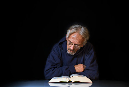 Portrait of a man with a book on black background