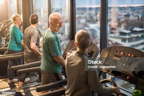 Happy Athletic Seniors Talking While Exercising On Treadmills In A Health Club Stock Photo - Download Image Now