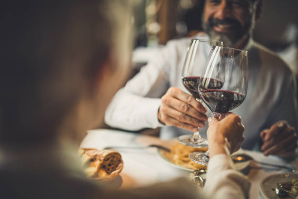 Close up of toasting with wine in a restaurant! Close up of a couple toasting with red wine during lunch in a restaurant. couple drinking stock pictures, royalty-free photos & images