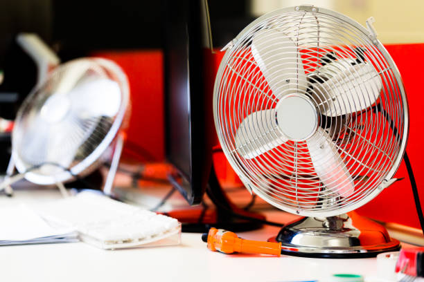 Small, portable switched off fan on desk in office stock photo