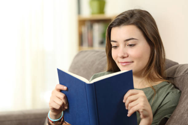 istock Teen reading a paper book on a sofa 950624518