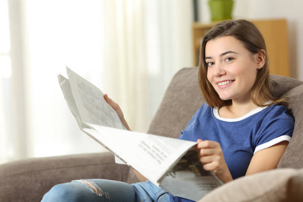 istock Teen reading a newspaper looking at camera at home 950624694