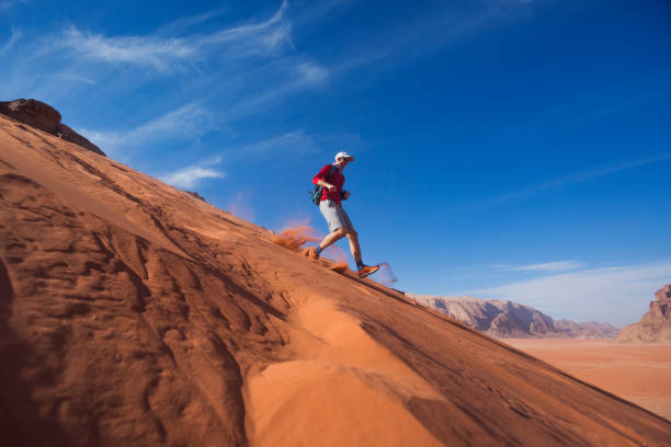 Man runs down the dune in the Wadi Rum desert, Jordan stock photo