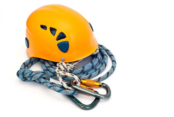 Isolated new climbing equipment - carabiner without scratches, orange helmet and blue rope
