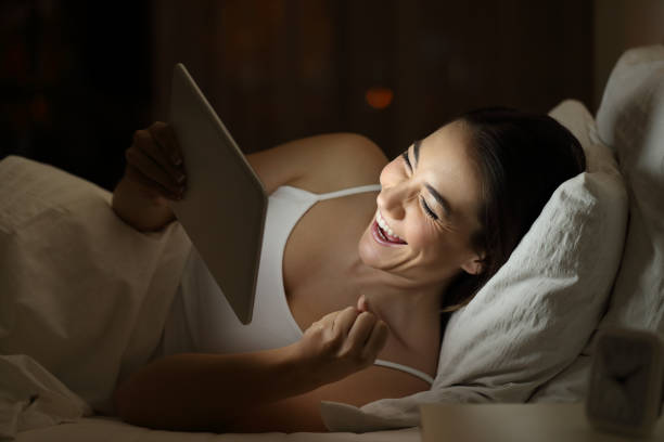 istock Excited woman using a tablet on the bed in the night 950629842
