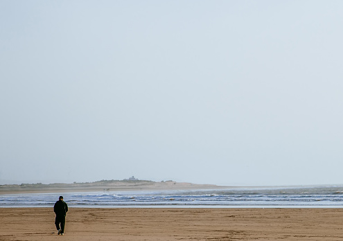 Essaouira,Morocco,28th March 2018: A man walking alone at beach in Essaouira,Morocco.