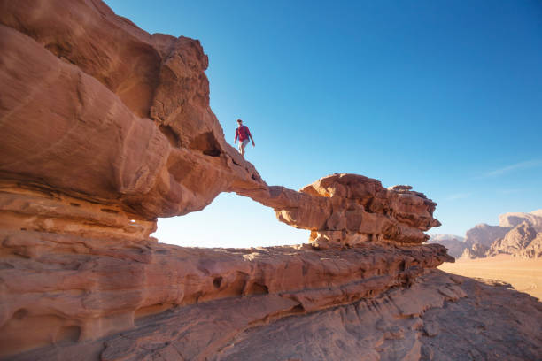 Tourist on rock. Wadi Ram desert. Stone bridge. Jordan landscape stock photo