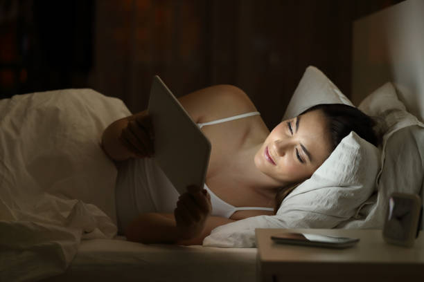 istock Relaxed girl using a tablet on the bed in the night 950635038