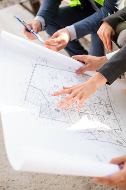 istock Young female architect showing floor plans to colleagues on a construction site 950638904