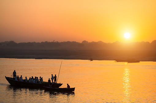 Silhouettes of Boats with pilgrims during sunset on the Holy Ganges river in Varanasi, India.