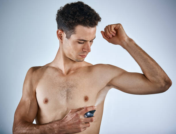 istock Handsome young man sprays underarms with deodorant 950646168