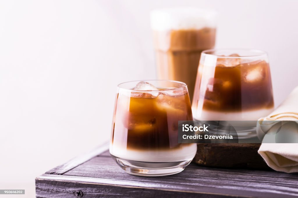 Iced coffee in glasses with milk. Black background Iced coffee in glasses with milk and cream. White background, wooden table. Horizontal view. Copy space Summer Stock Photo