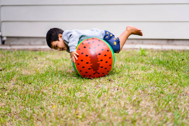 istock Kid in backyard playing with watermelon ball. 950654968