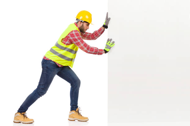 ouvrier du bâtiment mâle pousse un mur blanc - manual worker full length isolated on white standing photos et images de collection