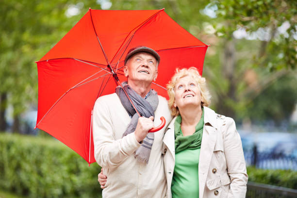 rain again - umbrella senior adult couple autumn imagens e fotografias de stock