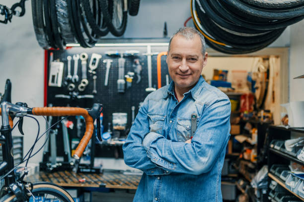 stylish bicycle mechanic standing in his workshop - bicycle gear fotos imagens e fotografias de stock