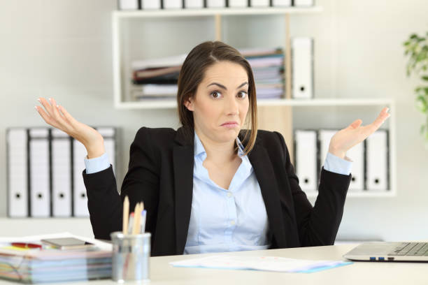 Confused businesswoman looking at camera Front view portrait of a confused businesswoman shrugging shoulders looking at camera at office skeptical look stock pictures, royalty-free photos & images