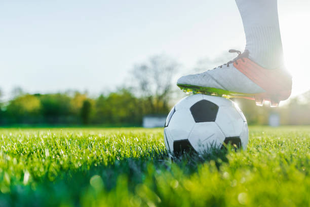 Close up view of balloon under football boots in park stock photo
